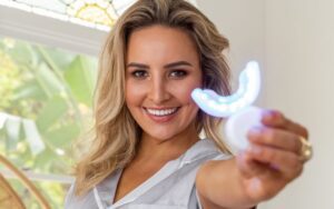 Person holding teeth whitening device.