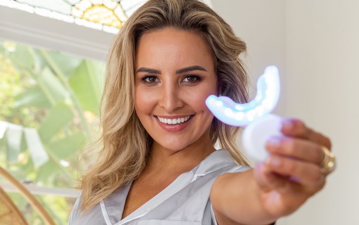 Person holding teeth whitening device.