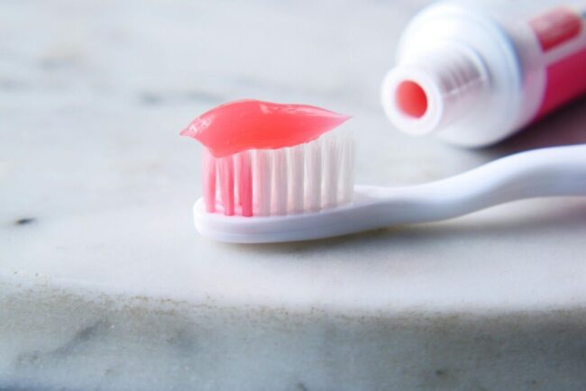 Toothbrush with pink toothpaste on marble