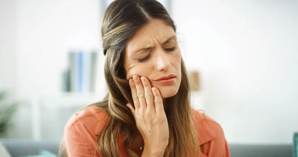 Woman experiencing tooth pain, a common dental emergency. Home dental care tips on our Homepage.