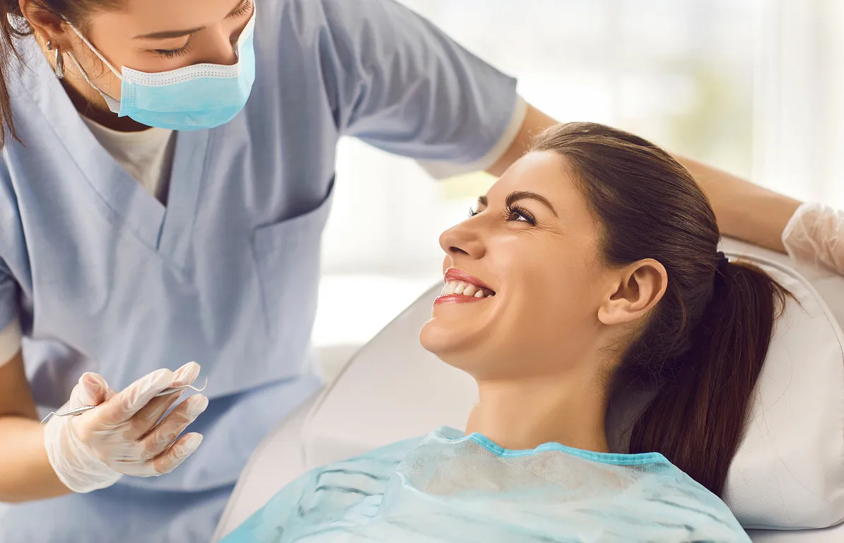 Woman smiling during a routine dental checkup. Healthy teeth examined by dentist. Homepage dental care.